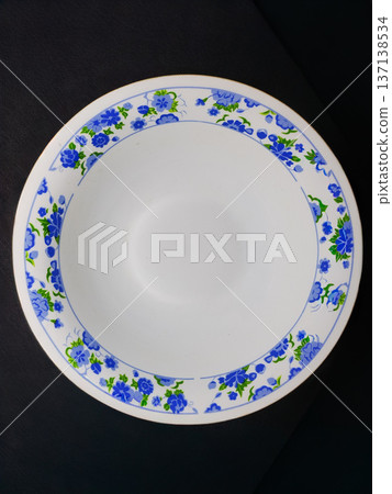 White plate with blue flowers on a black background. Top view White plate with blue flowers on a black background. Top view 137138534