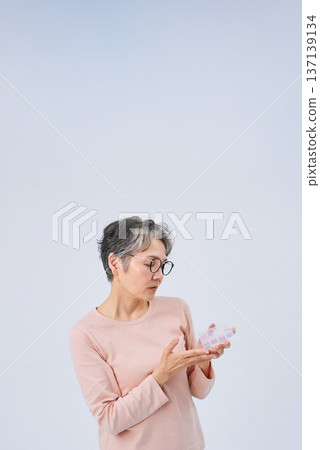 老婦人手裡拿著裝滿藥物的藥盒 老婦人手裡拿著裝滿藥物的藥盒 137139134