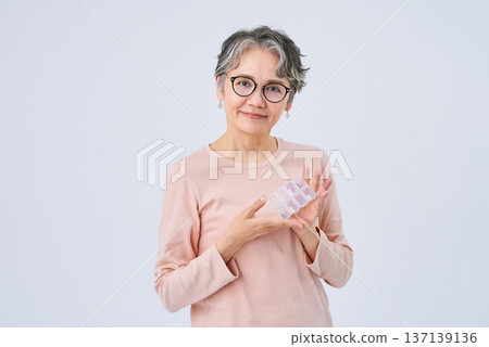 老婦人手裡拿著裝滿藥物的藥盒 137139136