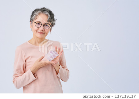 老婦人手裡拿著裝滿藥物的藥盒 137139137