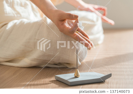 Incense burning in the room and the hands of a woman meditating in yoga 137140073