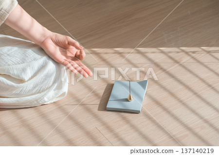 Incense burning in the room and the hands of a woman meditating in yoga Incense burning in the room and the hands of a woman meditating in yoga 137140219
