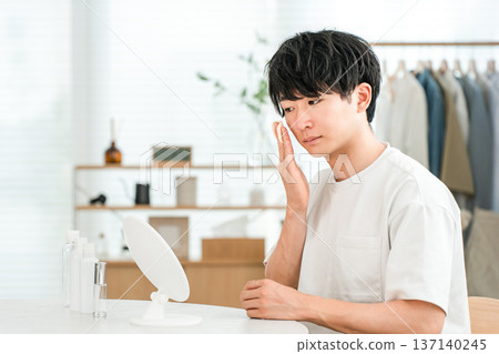 Young Asian man doing skin care, face care and moisturizing while looking in the mirror Young Asian man doing skin care, face care and moisturizing while looking in the mirror 137140245