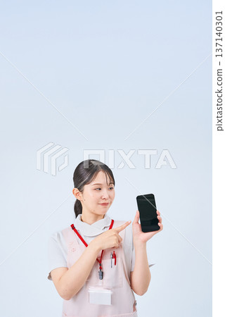 A young woman wearing a white coat and apron and holding a digital device A young woman wearing a white coat and apron and holding a digital device 137140301