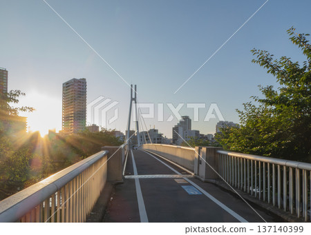 夕陽西下，照亮了河邊的人行橋。 137140399