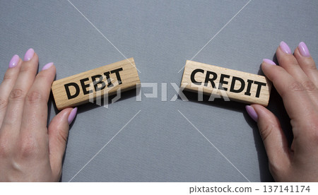 Debit or Credit symbol. Concept word Debit or Credit on wooden blocks. Businessman hand. Beautiful grey background. Business and Debit or Credit concept. Copy space 137141174
