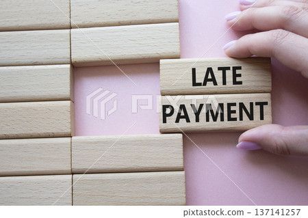 Late payment symbol. Concept word Late payment on wooden blocks. Beautiful pink background. Businessman hand. Business and Late payment concept. Copy space 137141257