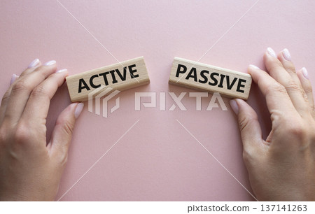 Active or Passive symbol. Concept word Active or Passive on wooden blocks. Businessman hand. Beautiful pink background. Business and Active or Passive concept. Copy space Active or Passive symbol. Concept word Active or Passive on wooden blocks. Businessman hand. Beautiful pink background. Business and Active or Passive concept. Copy space 137141263