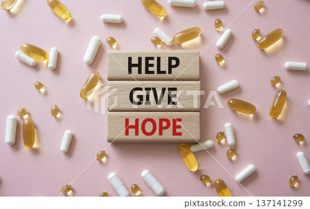 Help Give Hope symbol. Concept word Help Give Hope on wooden blocks. Beautiful pink background with pills. Medicine and Help Give Hope concept. Copy space 137141299