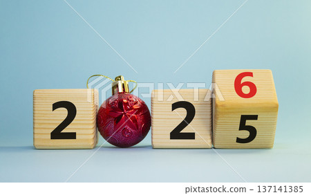 2026 New Year symbol. Businessman turns wooden cube and changes Year 2025 to 2026. Beautiful light blue background with Christmas ball. Copy space. Business and 2026 happy new year concept 2026 New Year symbol. Businessman turns wooden cube and changes Year 2025 to 2026. Beautiful light blue background with Christmas ball. Copy space. Business and 2026 happy new year concept 137141385