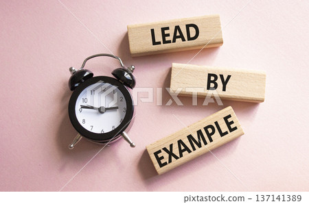 Lead by Example symbol. Concept word Lead by Example on wooden cubes. Beautiful pink background with alarm clock. Business and Lead by Example concept. Copy space. 137141389