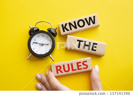 Know the rules symbol. Wooden blocks with words Know the rules. Businessman hand. Beautiful yellow background with alarm clock. Business and Know the rules concept. Copy space. Know the rules symbol. Wooden blocks with words Know the rules. Businessman hand. Beautiful yellow background with alarm clock. Business and Know the rules concept. Copy space. 137141399