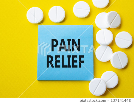 Pain Relief symbol. Concept word Pain Relief on blue note. Beautiful yellow background with pills. Medicine and Pain Relief concept. Copy space Pain Relief symbol. Concept word Pain Relief on blue note. Beautiful yellow background with pills. Medicine and Pain Relief concept. Copy space 137141448