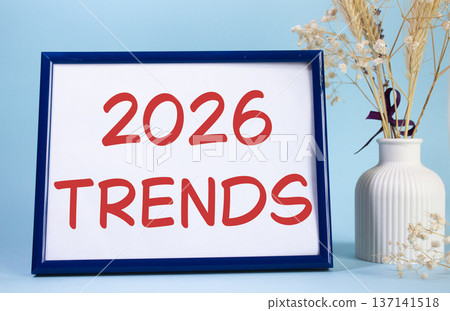 2026 Trends symbol. Concept words 2026 Trends on beautiful wooden picture frame. Beautiful light blue background with flower vase. Business and 2026 Trends concept. Copy space. 137141518