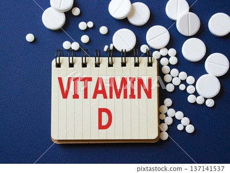 Vitamin D symbol. Concept word Vitamin D on notebook. Beautiful deep blue background with pills. Medicine and Vitamin D concept. Copy space Vitamin D symbol. Concept word Vitamin D on notebook. Beautiful deep blue background with pills. Medicine and Vitamin D concept. Copy space 137141537
