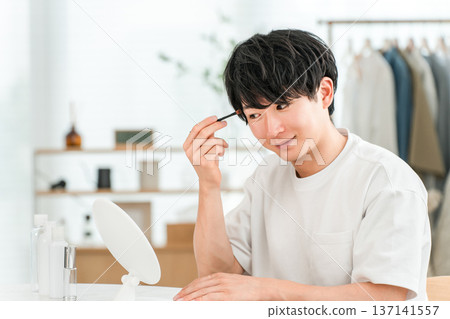 年輕的亞洲男子正在用化妝筆畫眼妝 137141557