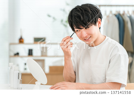 年輕的亞洲男子正在用化妝筆畫眼妝 年輕的亞洲男子正在用化妝筆畫眼妝 137141558