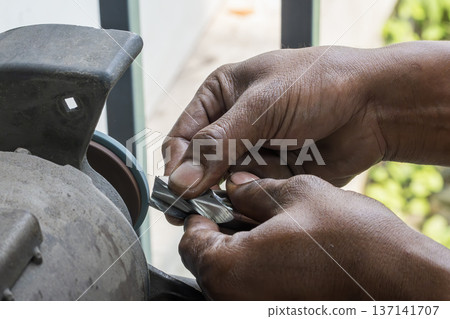 Skilled operator performing manual regrinding of a flat nose end mill to restore cutting edge geometry and tool life. Skilled operator performing manual regrinding of a flat nose end mill to restore cutting edge geometry and tool life. 137141707