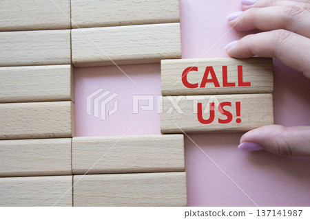 Call Us symbol. Wooden blocks with words Call Us. Businessman hand. Beautiful pink background. Business and Call Us concept. Copy space. 137141987