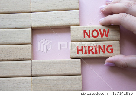 Now Hiring symbol. Concept word Now Hiring on wooden blocks. Businessman hand. Beautiful pink background. Business and Now Hiring concept. Copy space Now Hiring symbol. Concept word Now Hiring on wooden blocks. Businessman hand. Beautiful pink background. Business and Now Hiring concept. Copy space 137141989