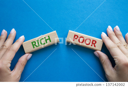 Rich vs Poor symbol. Concept word Rich vs Poor on wooden blocks. Businessman hand. Beautiful blue background. Business and Rich vs Poor concept. Copy space Rich vs Poor symbol. Concept word Rich vs Poor on wooden blocks. Businessman hand. Beautiful blue background. Business and Rich vs Poor concept. Copy space 137142002
