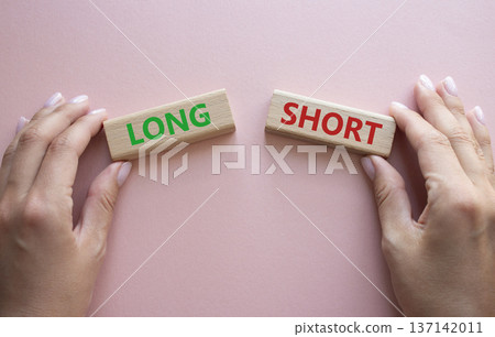Short vs Long symbol. Concept word Short vs Long on wooden blocks. Businessman hand. Beautiful pink background. Business and Short vs Long concept. Copy space 137142011