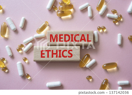 Medical Ethics symbol. Concept word Medical Ethics on wooden blocks. Beautiful pink background with pills. Medicine and Medical Ethics concept. Copy space 137142036