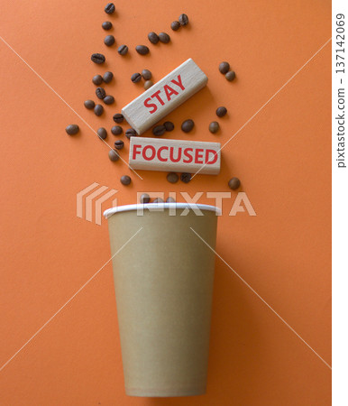 Stay Focused symbol. Concept word Stay Focused on wooden blocks. Beautiful orange background with coffee cup. Business and Stay Focused concept. Copy space 137142069