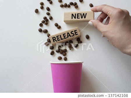 New Release symbol. Concept word New Release on wooden blocks. Businessman hand. Beautiful white background with coffee cup. Business and New Release concept. Copy space New Release symbol. Concept word New Release on wooden blocks. Businessman hand. Beautiful white background with coffee cup. Business and New Release concept. Copy space 137142108
