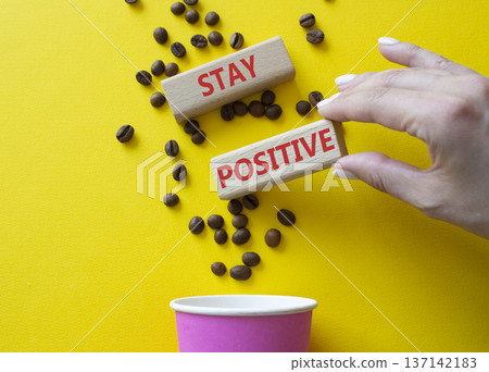 Stay Positive symbol. Concept word Stay Positive on wooden blocks. Businessman hand. Beautiful yellow background with coffee cup. Business and Stay Positive concept. Copy space Stay Positive symbol. Concept word Stay Positive on wooden blocks. Businessman hand. Beautiful yellow background with coffee cup. Business and Stay Positive concept. Copy space 137142183