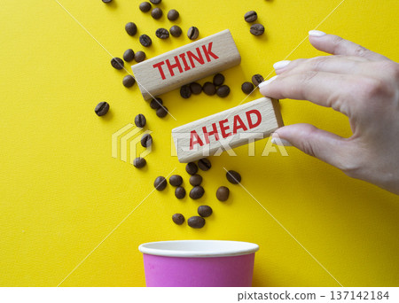 Think ahead symbol. Concept word Think ahead on wooden blocks. Businessman hand. Beautiful yellow background with coffee cup. Business and Think ahead concept. Copy space Think ahead symbol. Concept word Think ahead on wooden blocks. Businessman hand. Beautiful yellow background with coffee cup. Business and Think ahead concept. Copy space 137142184