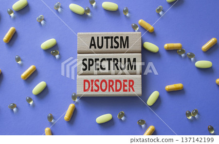 Autism Spectrum Disorder symbol. Concept word Autism Spectrum Disorder on wooden blocks. Beautiful purple background with pills. Medicine and Autism Spectrum Disorder concept. Copy space Autism Spectrum Disorder symbol. Concept word Autism Spectrum Disorder on wooden blocks. Beautiful purple background with pills. Medicine and Autism Spectrum Disorder concept. Copy space 137142199