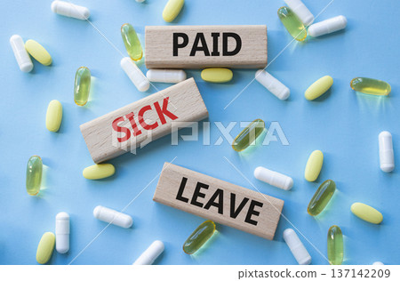 Paid Sick Leave symbol. Concept words Paid Sick Leave on wooden blocks. Beautiful blue background with pills. Healthcare and Paid Sick Leave concept. Copy space. Paid Sick Leave symbol. Concept words Paid Sick Leave on wooden blocks. Beautiful blue background with pills. Healthcare and Paid Sick Leave concept. Copy space. 137142209
