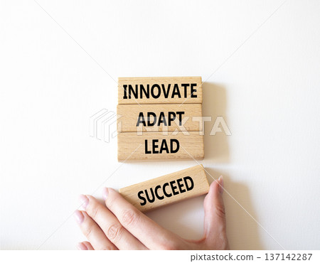 Innovate Adapt Lead Succeed symbol. Concept words Innovate Adapt Lead Succeed on wooden blocks. Beautiful bright white background. Businessman hand. Business and Innovate Adapt Lead Succeed concept. 137142287