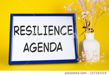 Resilience agenda symbol. Concept words Resilience agenda on beautiful wooden picture frame. Beautiful yellow background with flower vase. Business and Resilience agenda concept. Copy space. Resilience agenda symbol. Concept words Resilience agenda on beautiful wooden picture frame. Beautiful yellow background with flower vase. Business and Resilience agenda concept. Copy space. 137142314