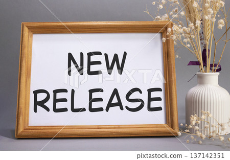 New Release symbol. Concept words New Release on beautiful wooden picture frame. Beautiful grey background with flower vase. Business and New Release concept. Copy space. New Release symbol. Concept words New Release on beautiful wooden picture frame. Beautiful grey background with flower vase. Business and New Release concept. Copy space. 137142351