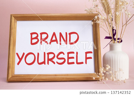 Brand yourself symbol. Concept words Brand yourself on beautiful wooden picture frame. Beautiful pink background with flower vase. Business and Brand yourself concept. Copy space. Brand yourself symbol. Concept words Brand yourself on beautiful wooden picture frame. Beautiful pink background with flower vase. Business and Brand yourself concept. Copy space. 137142352