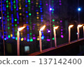 Glowing white candles on balcony railing with colorful festive bokeh background 137142400