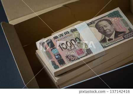 A stack of bills in a cardboard box. A dark image. A stack of bills in a cardboard box. A dark image. 137142416