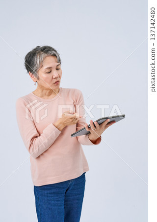 Senior woman holding a digital device Senior woman holding a digital device 137142480