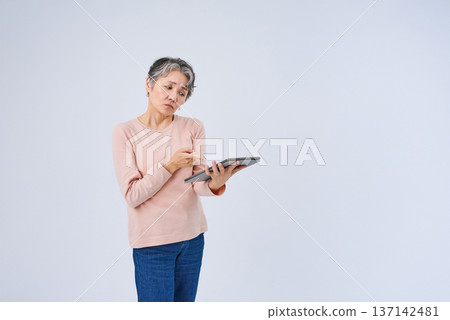 Senior woman holding a digital device Senior woman holding a digital device 137142481