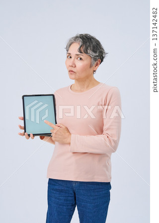 Senior woman holding a digital device 137142482