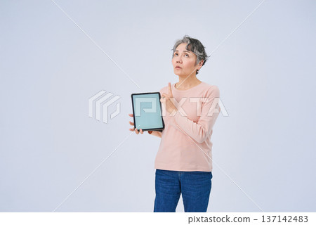 Senior woman holding a digital device Senior woman holding a digital device 137142483