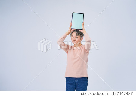 Senior woman holding a digital device Senior woman holding a digital device 137142487