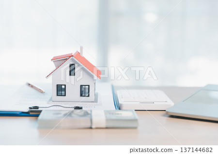Home buying and mortgage planning concept for real estate investment and insurance, featuring a miniature house, keys, calculator, pen and contract on a bright desk in a modern office. real estate Home buying and mortgage planning concept for real estate investment and insurance, featuring a miniature house, keys, calculator, pen and contract on a bright desk in a modern office. real estate 137144682