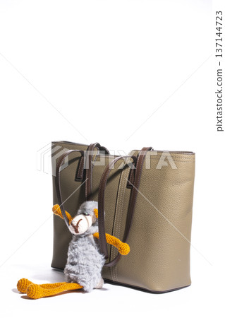 Women's beige leather bag with a toy on a white background 137144723