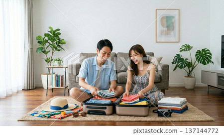 Smiling couple enjoying preparing for summer travel in the living room Smiling couple enjoying preparing for summer travel in the living room 137144772