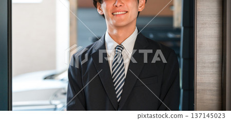 Smiling young Asian man in a suit returning home Smiling young Asian man in a suit returning home 137145023