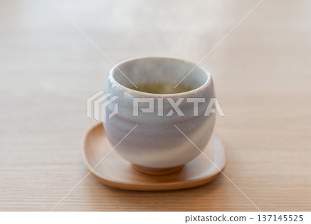 Freshly brewed green tea with steam rising from a teacup Freshly brewed green tea with steam rising from a teacup 137145525