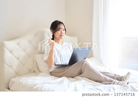A woman pumping her fist while looking at a computer 137145718